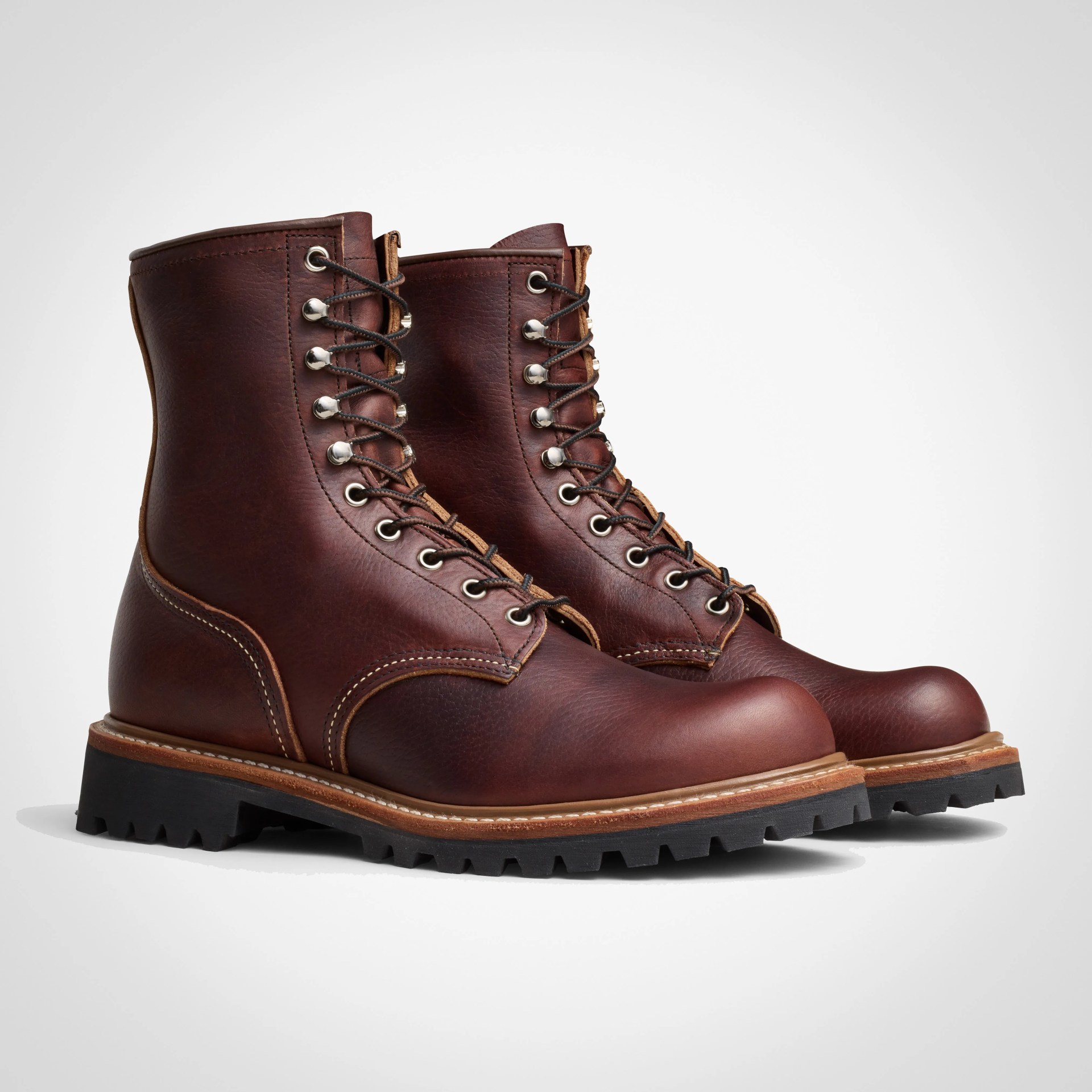 Pair of brown leather lace-up boots with black lug soles on a white background.