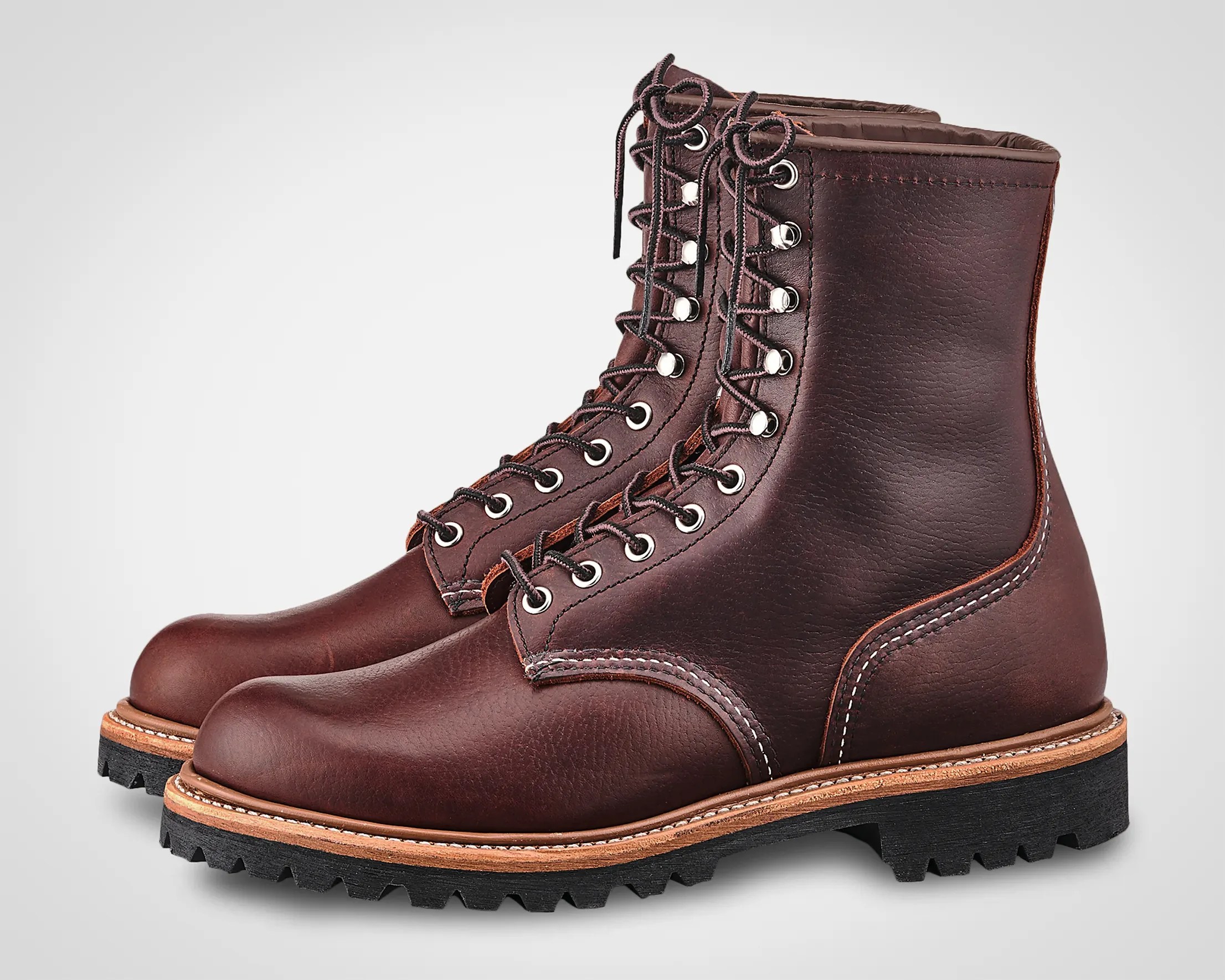Pair of dark brown leather lace-up boots with black lug soles and tan welt stitching.