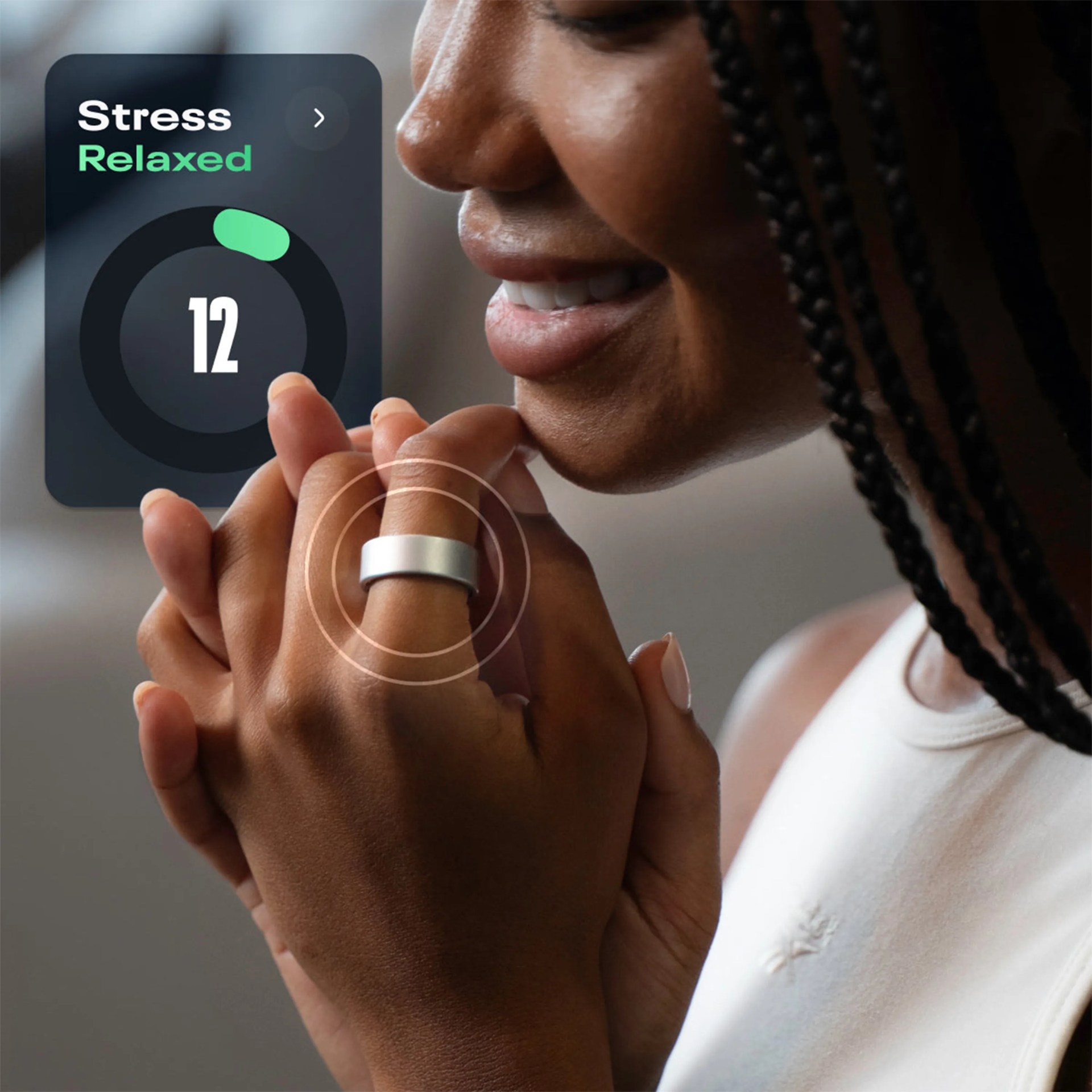 Person wearing a silver smart ring on their finger with a stress-relaxed app display showing the number 12.