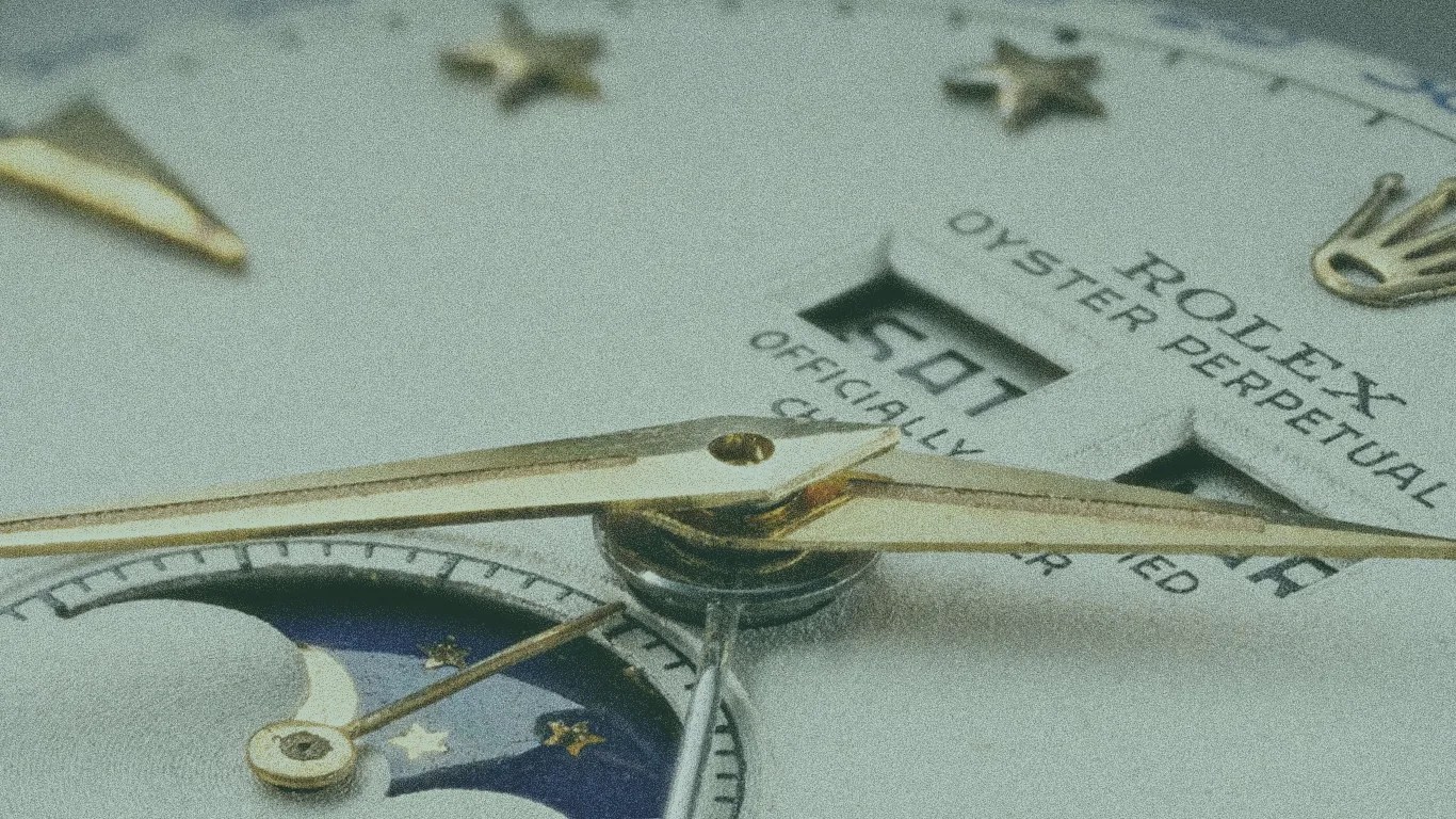 Close-up of a Rolex Oyster Perpetual watch face showing gold hands, date window, and moon phase indicator.
