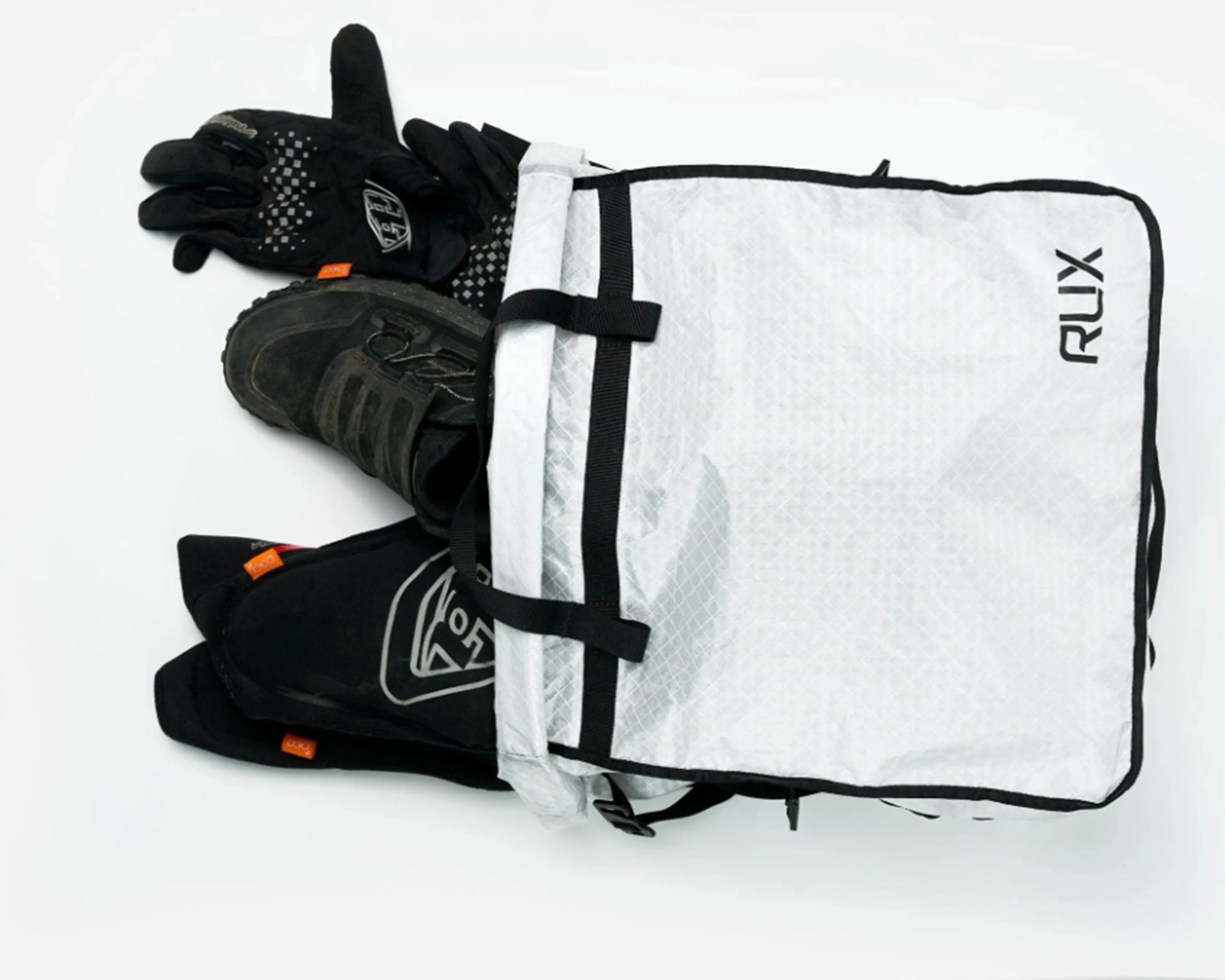 White RUX backpack with black trim partially open showing black gloves, boots, and knee pads inside.