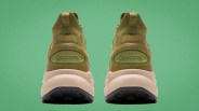 Pair of olive green Saucony sneakers shown from the back with beige midsoles and black outsoles on a green background.
