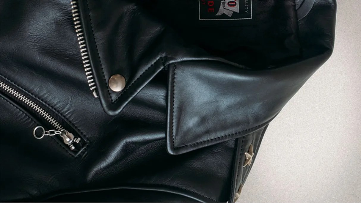 Black leather jacket with silver zipper and snap button details, showing a folded collar.