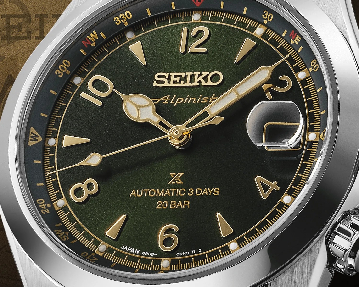 Close-up of a Seiko Alpinist watch face with green dial, gold numerals and hands, date magnifier, and stainless steel case.