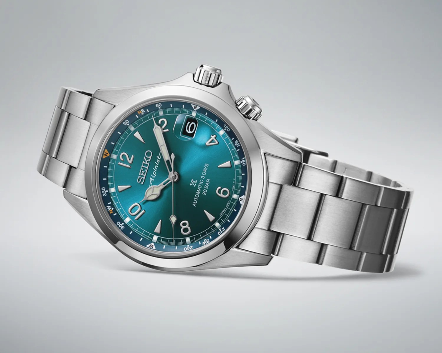 Silver stainless steel Seiko wristwatch with teal dial and date magnifier at 3 o'clock.