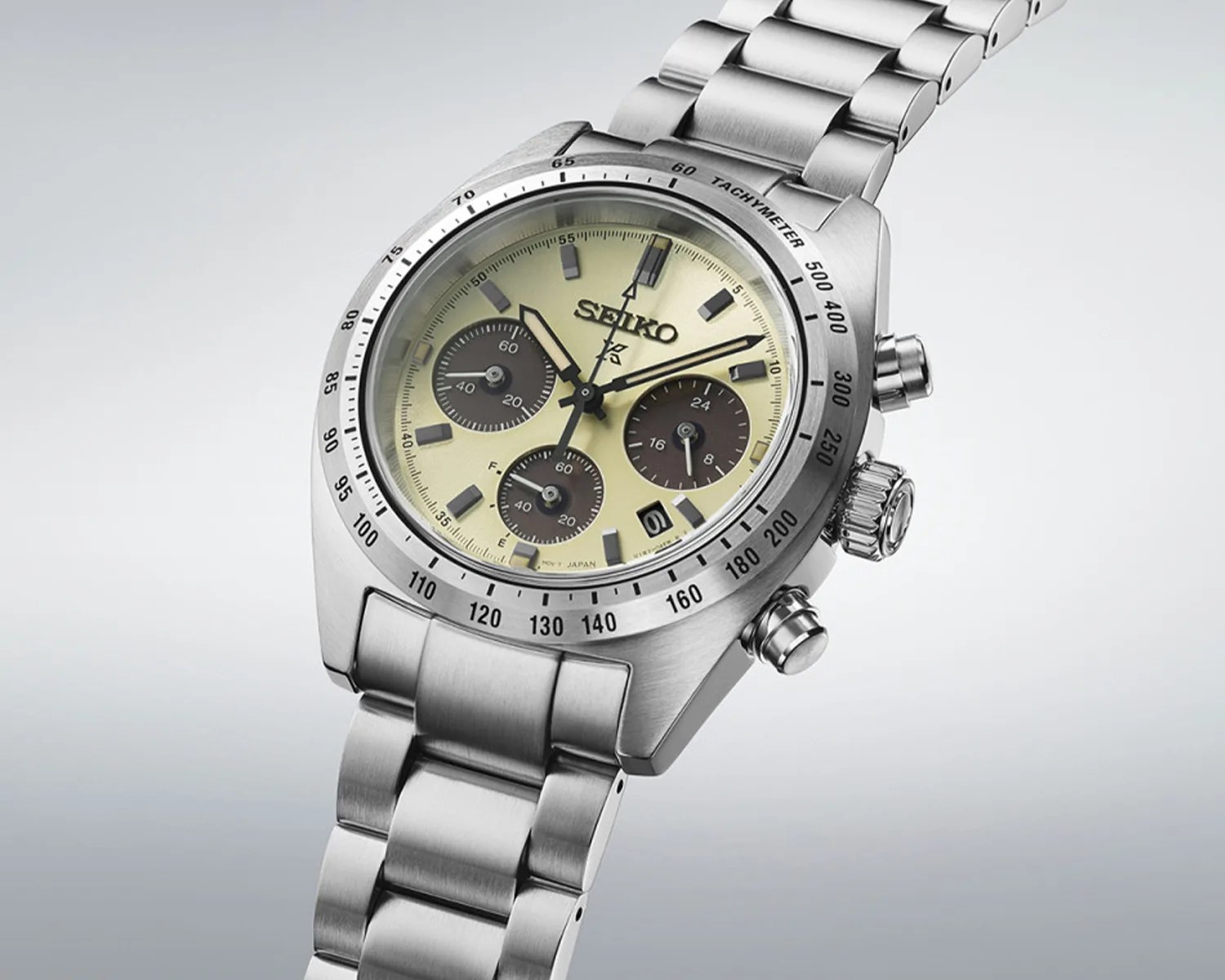 Stainless steel Seiko chronograph watch with beige dial, three subdials, date window, and tachymeter bezel.