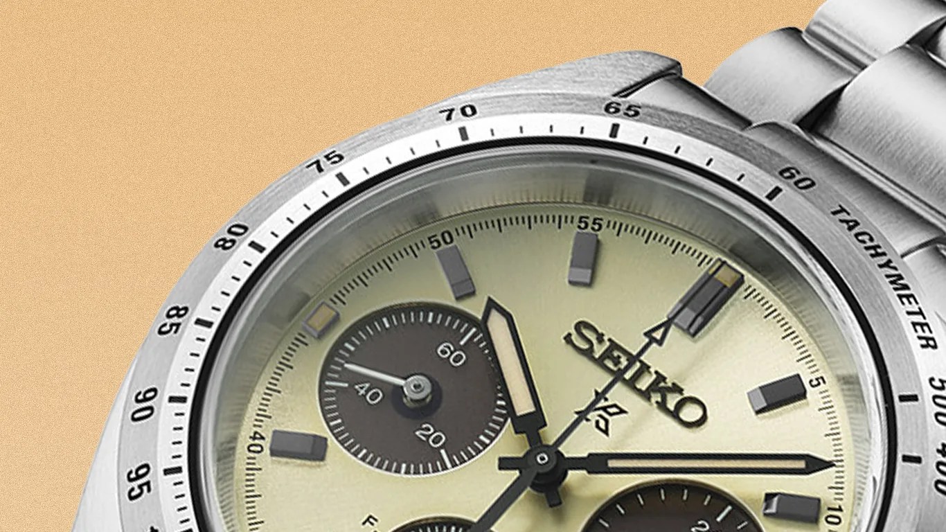 Close-up of a Seiko wristwatch with a cream dial, black subdials, and a stainless steel tachymeter bezel and bracelet.