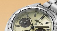 Close-up of a Seiko wristwatch with a cream dial, black subdials, and a stainless steel tachymeter bezel and bracelet.