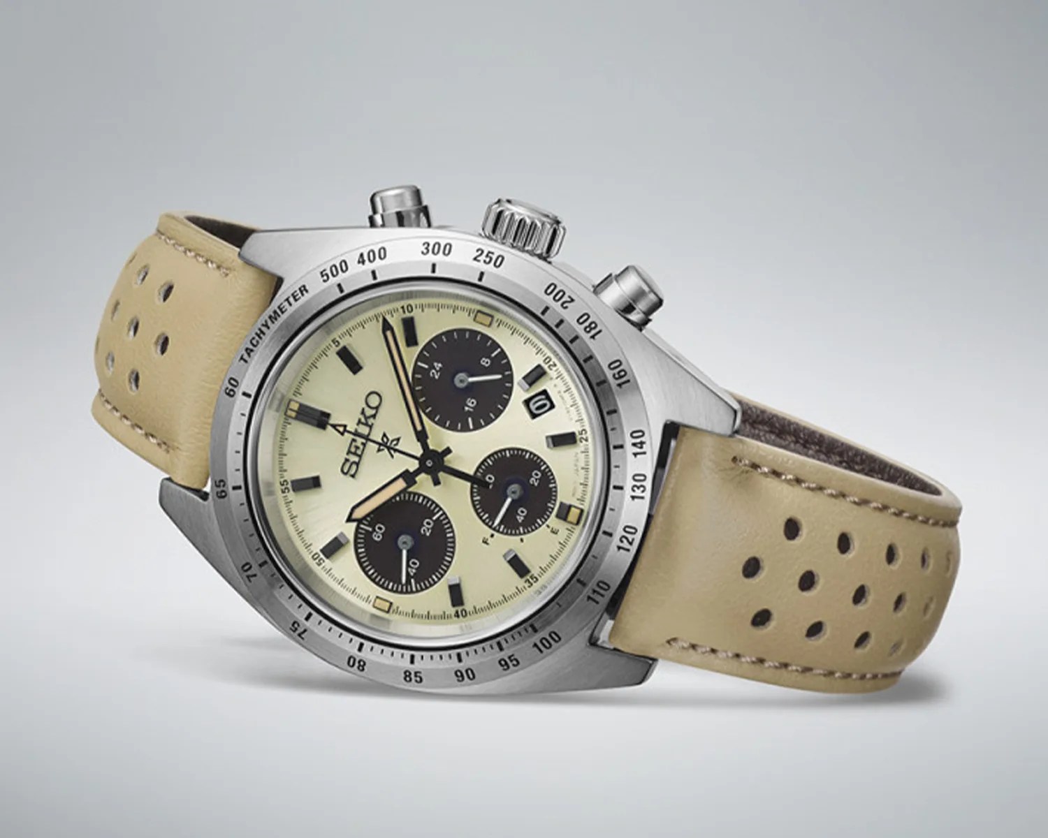 Seiko chronograph watch with cream dial, black subdials, stainless steel case, and perforated beige leather strap.