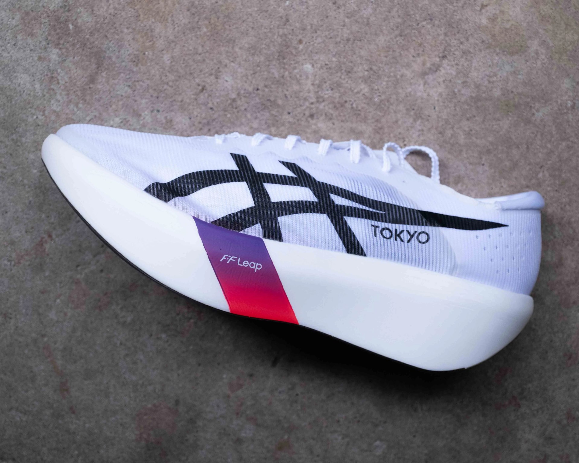 White running shoe with black stripes, "TOKYO" text, and a white sole featuring a purple-red gradient section labeled "FF Leap.