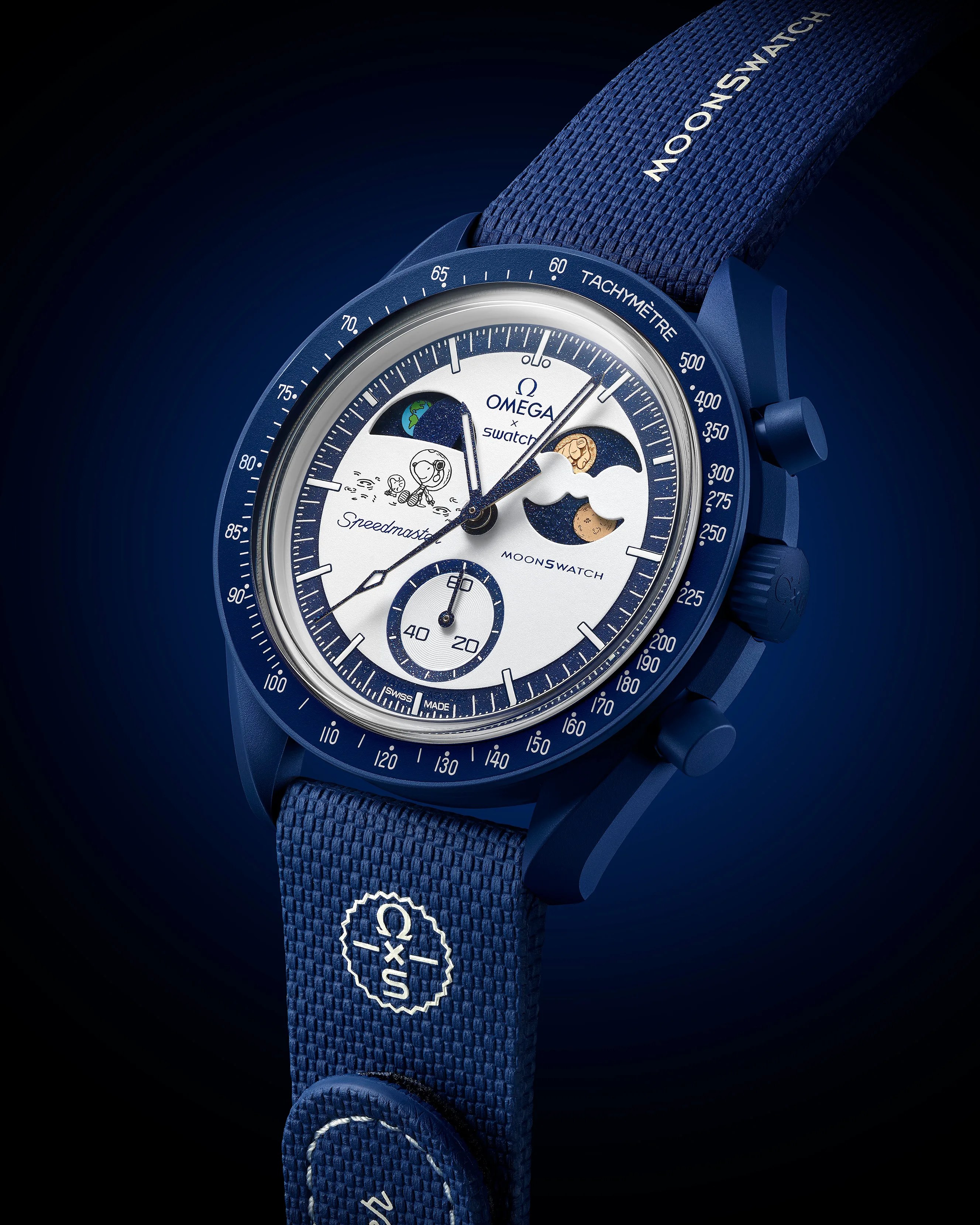 Blue Omega x Swatch Moonswatch with white dial featuring cartoon astronaut and moon phases, blue fabric strap with logo.