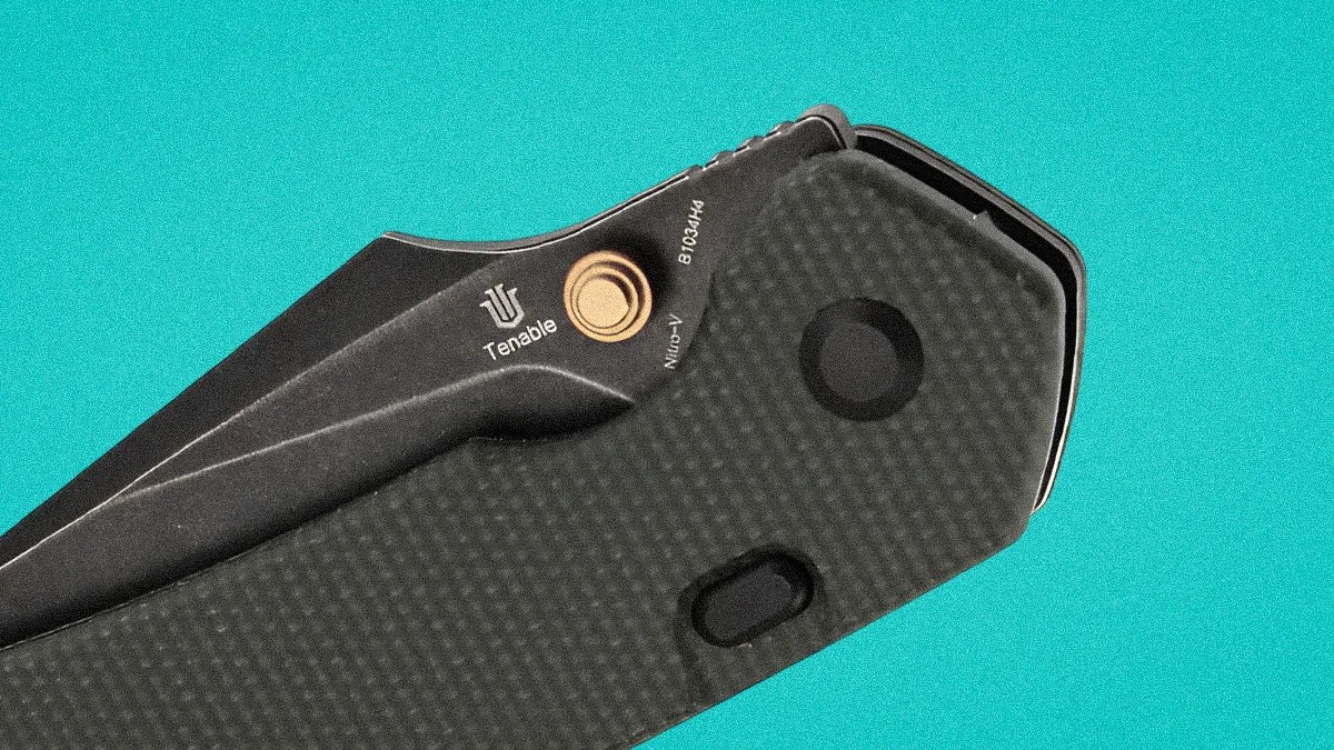 Black folding knife with textured handle and Tenable logo on the blade against a turquoise background.
