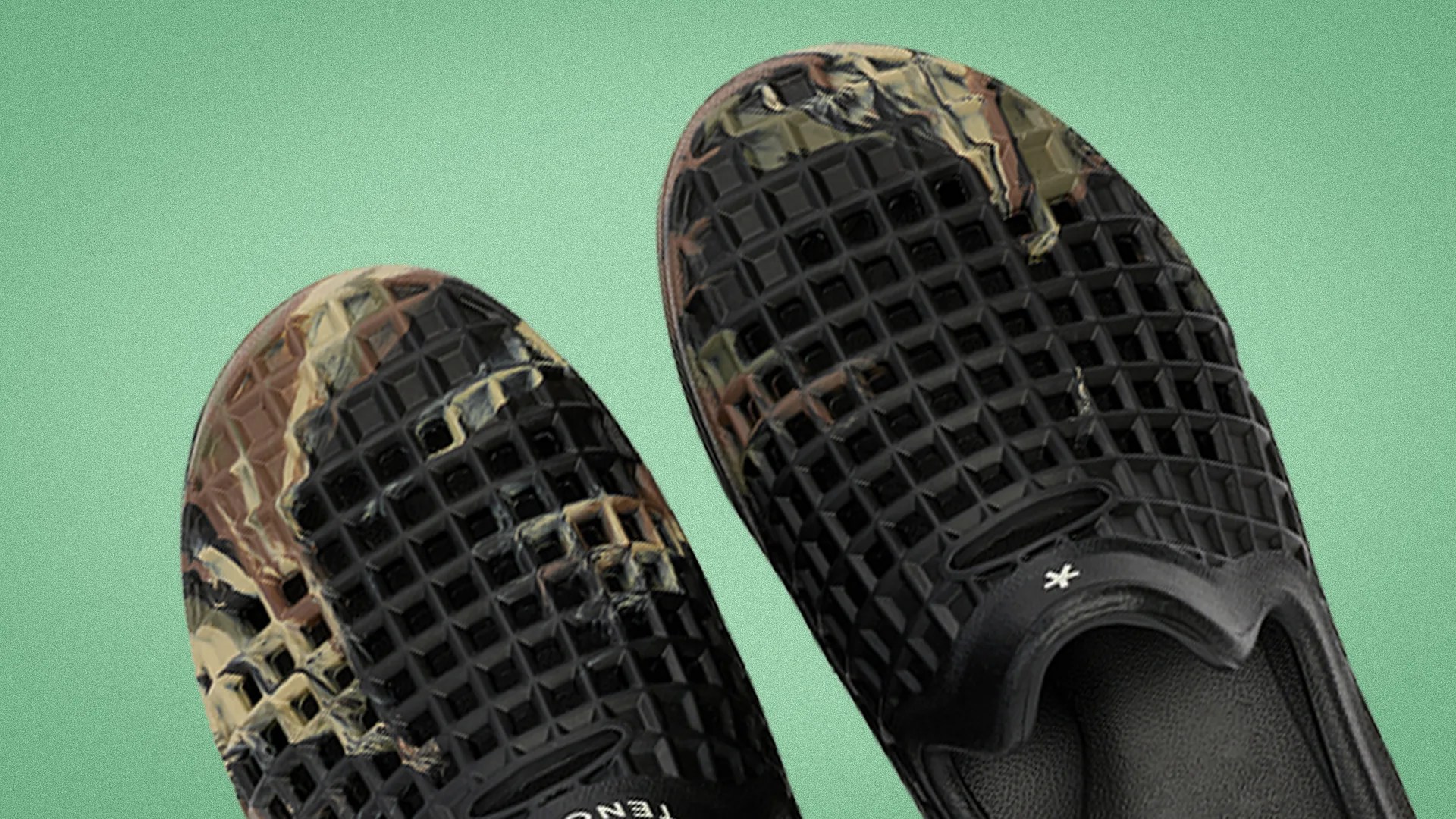 Pair of black slip-on shoes with a textured grid pattern and camouflage accents on a green background.