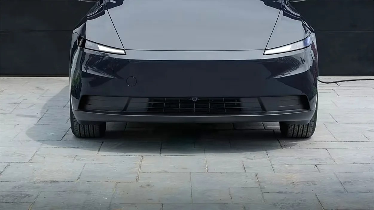 Front view of a sleek black electric car with narrow LED headlights on a stone driveway.
