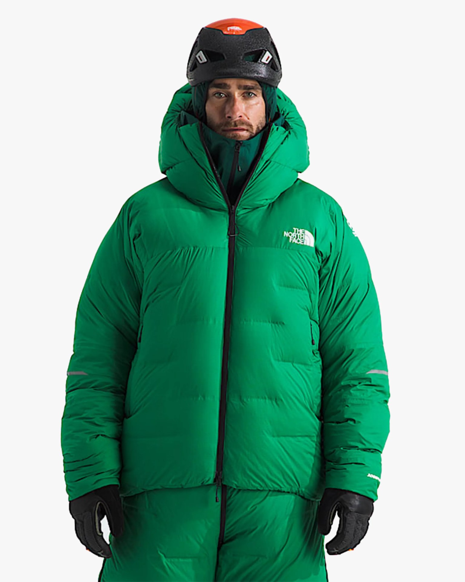 Man wearing a bright green insulated North Face jacket, black gloves, and a black climbing helmet with an orange top.