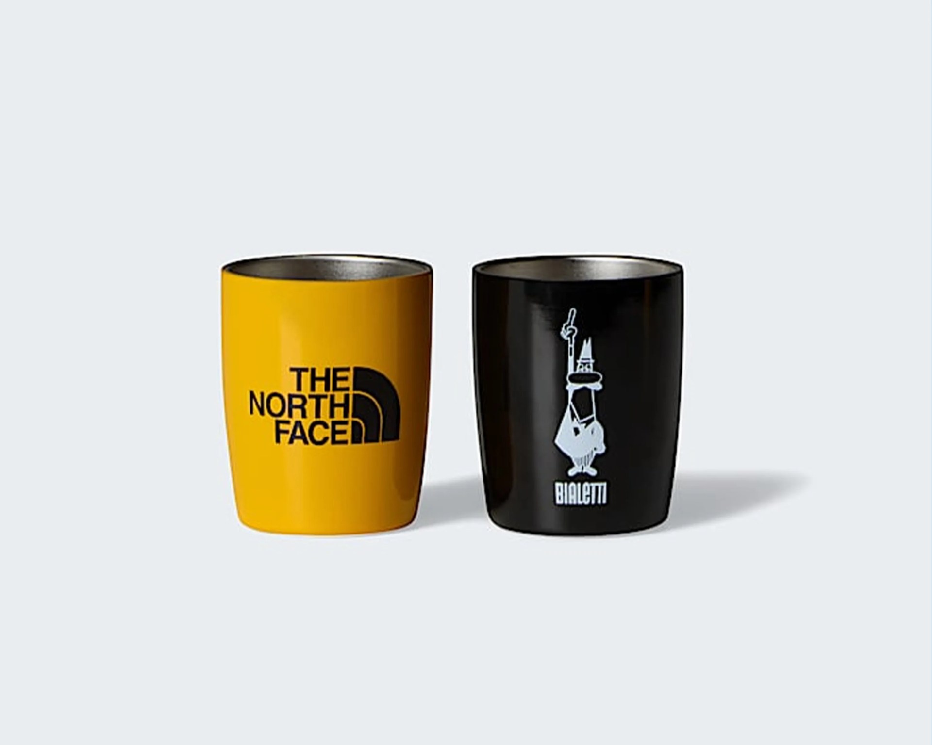 Two stainless steel tumblers, one yellow with The North Face logo and one black with Bialetti logo.