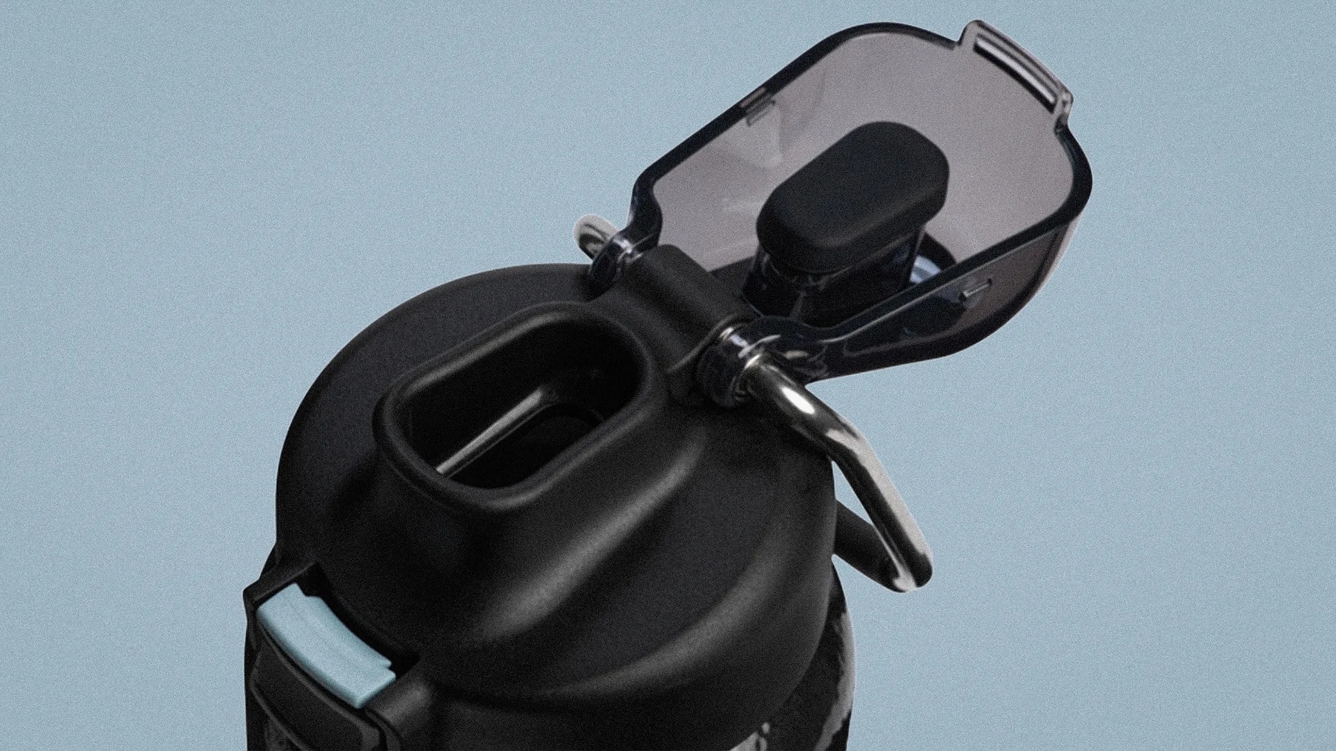 Black water bottle lid with a flip-top transparent cap and a metal handle against a light blue background.