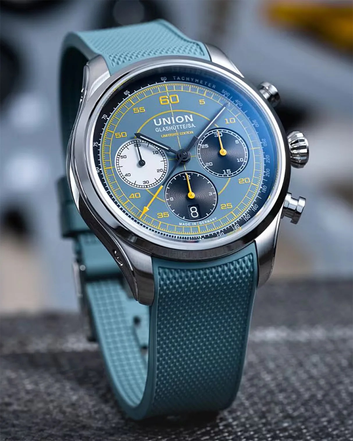 Union Glashütte wristwatch with blue dial, yellow accents, three subdials, and textured blue rubber strap.