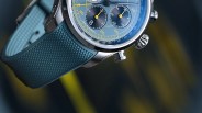 Blue chronograph wristwatch with yellow accents and textured blue rubber strap.