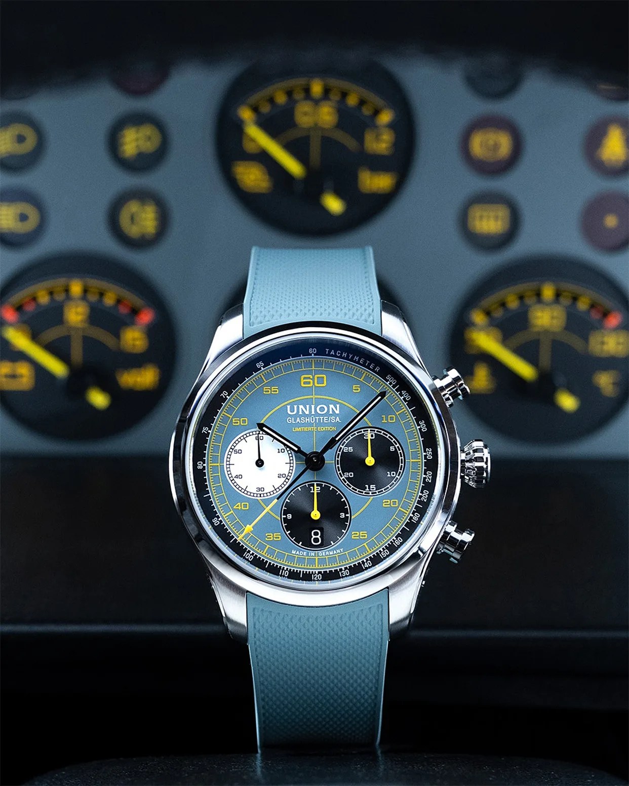 Union Glashütte chronograph watch with blue dial, yellow accents, three subdials, and blue textured strap.