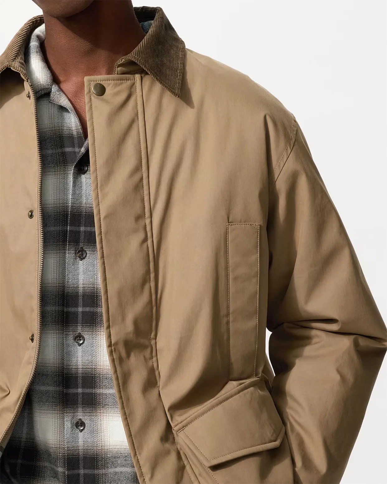 Tan jacket with corduroy collar worn over a black and white plaid button-up shirt.