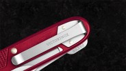 Close-up of a red Victorinox pocket knife with a silver clip and "PRESS" tab on a black surface.