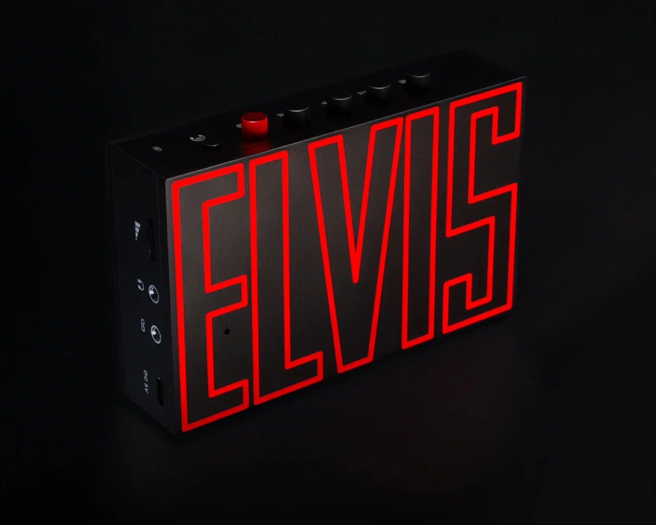Black rectangular electronic device with red outline text "ELVIS" and multiple control knobs on top.