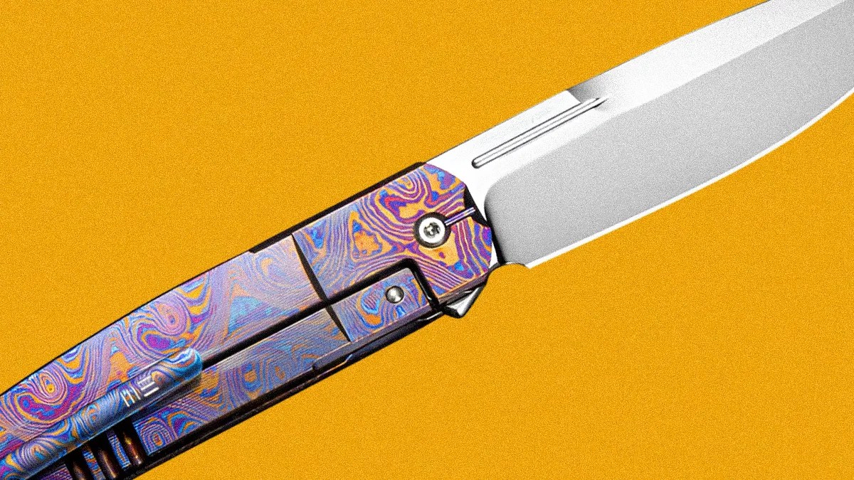 Folding knife with a polished silver blade and a handle featuring a colorful, swirling pattern on a yellow background.