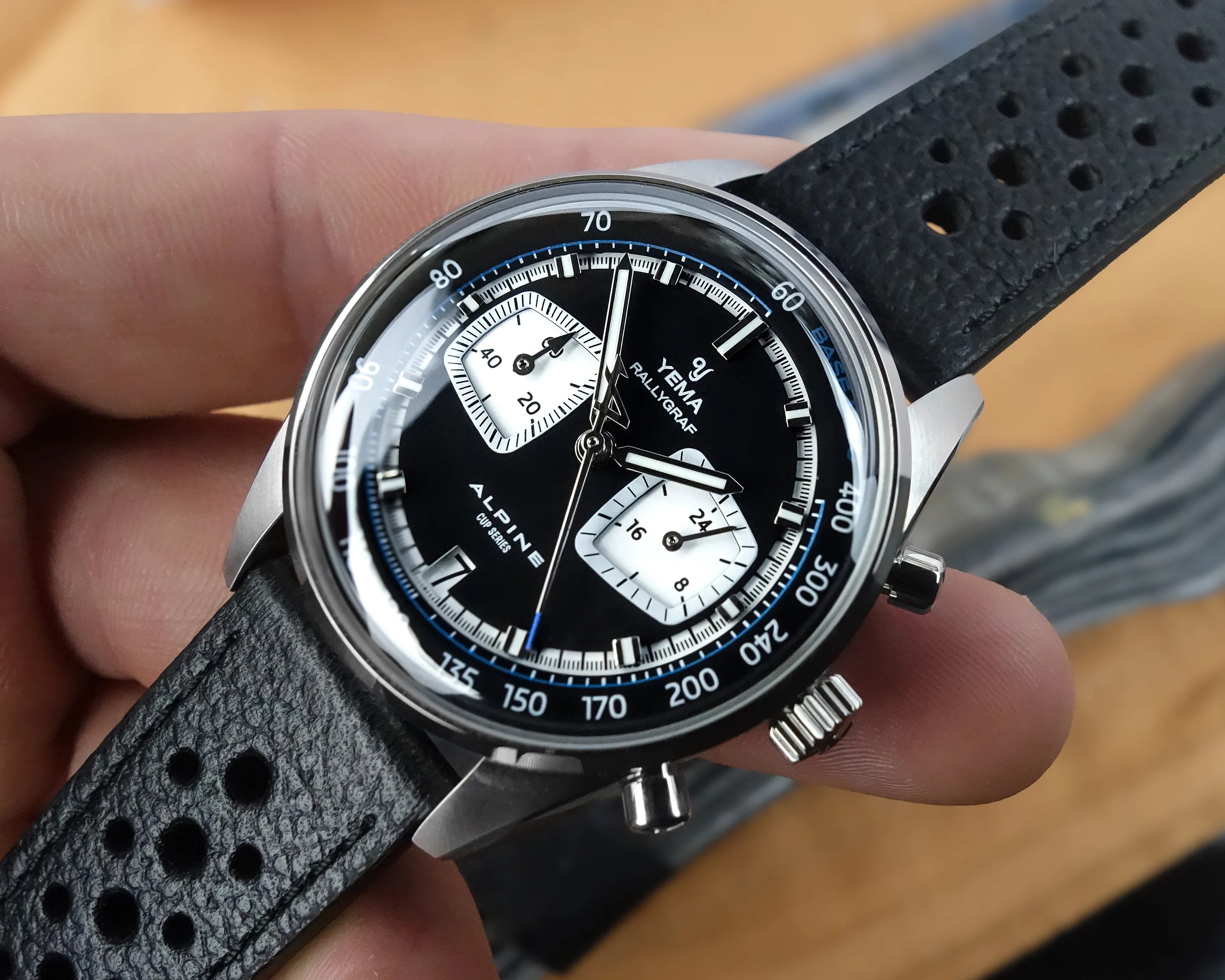 Close-up of a Yema Rallygraf Alpine Cup Series wristwatch with black dial, two white subdials, and perforated black leather strap.