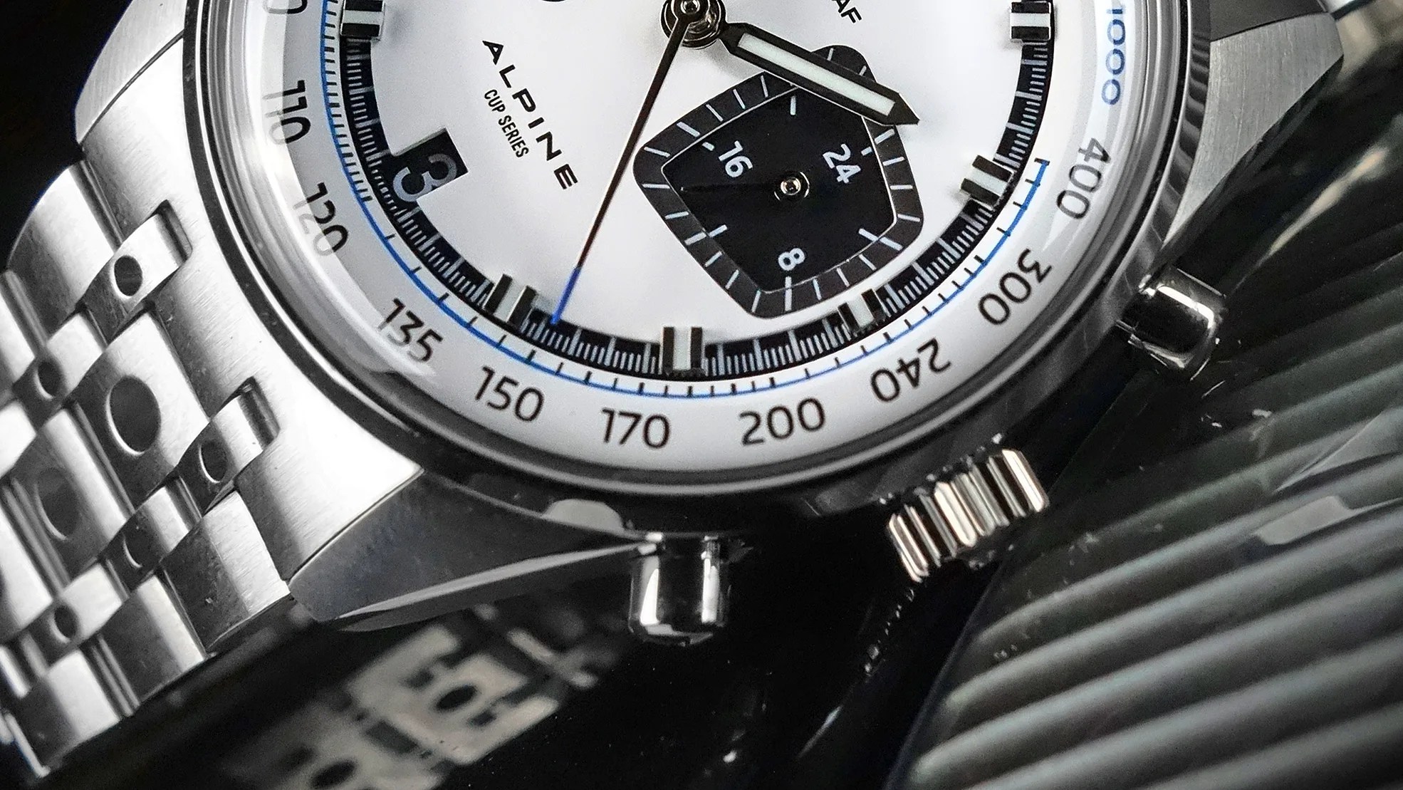 Close-up of a stainless steel Alpine Cup Series wristwatch with a white dial and black subdial.