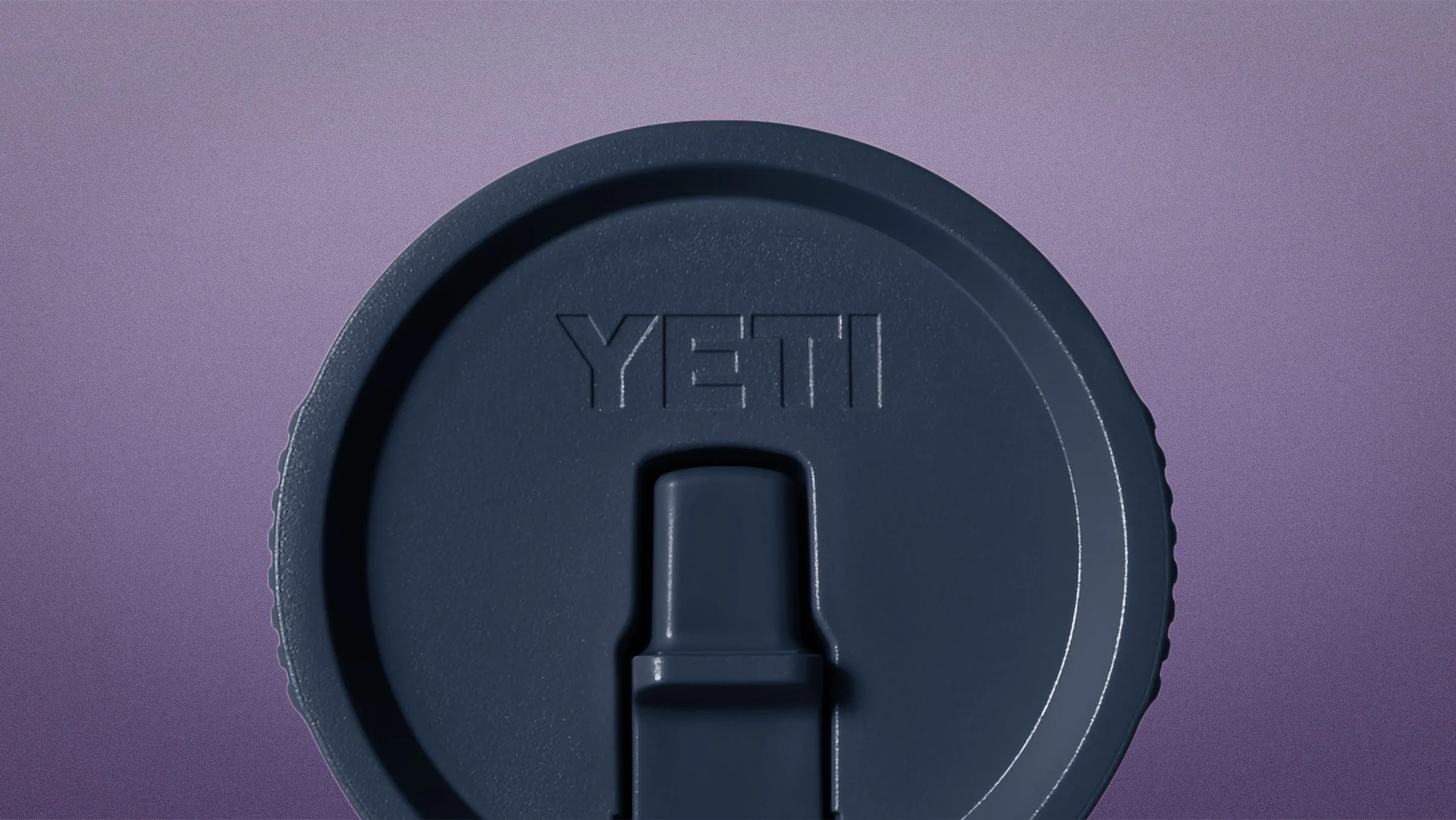 Dark blue YETI branded plastic lid with a sliding closure on a purple background.