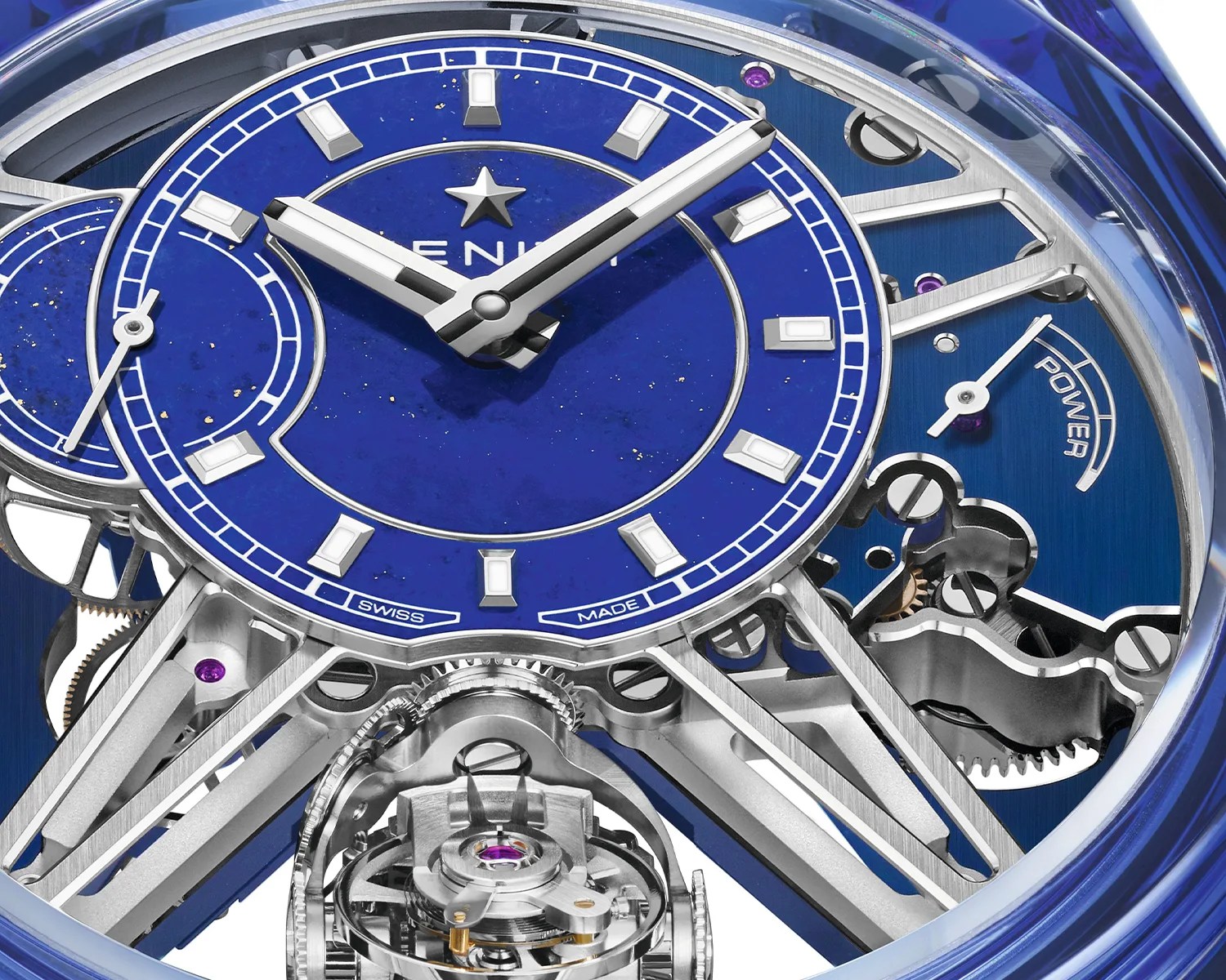Close-up of a luxury watch face with a deep blue dial, silver hour markers, and visible mechanical components.