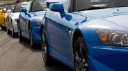 Line of blue, white, and yellow Honda S2000 sports cars parked on asphalt.