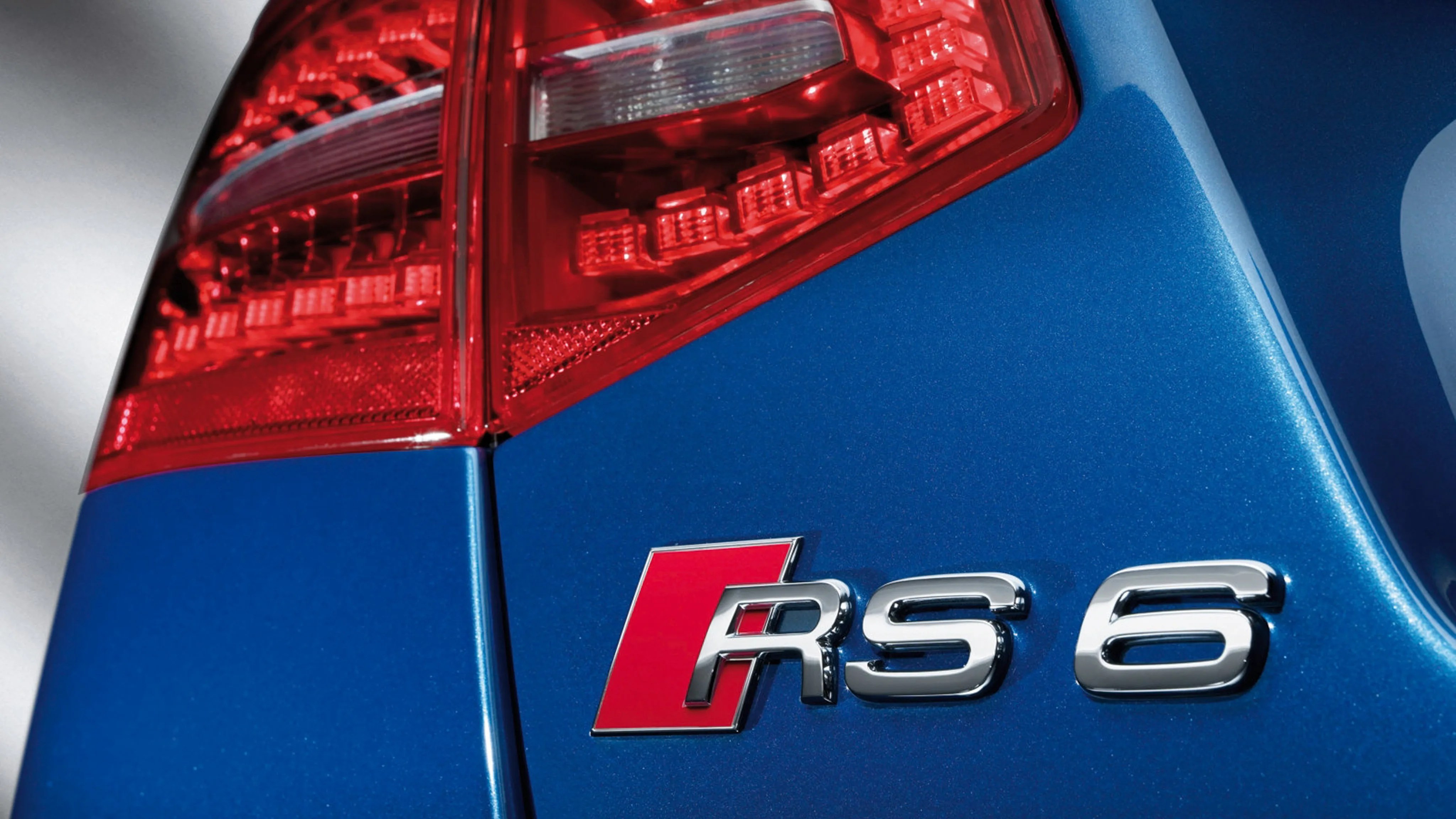 Close-up of a blue car's rear with red taillight and chrome RS 6 badge.