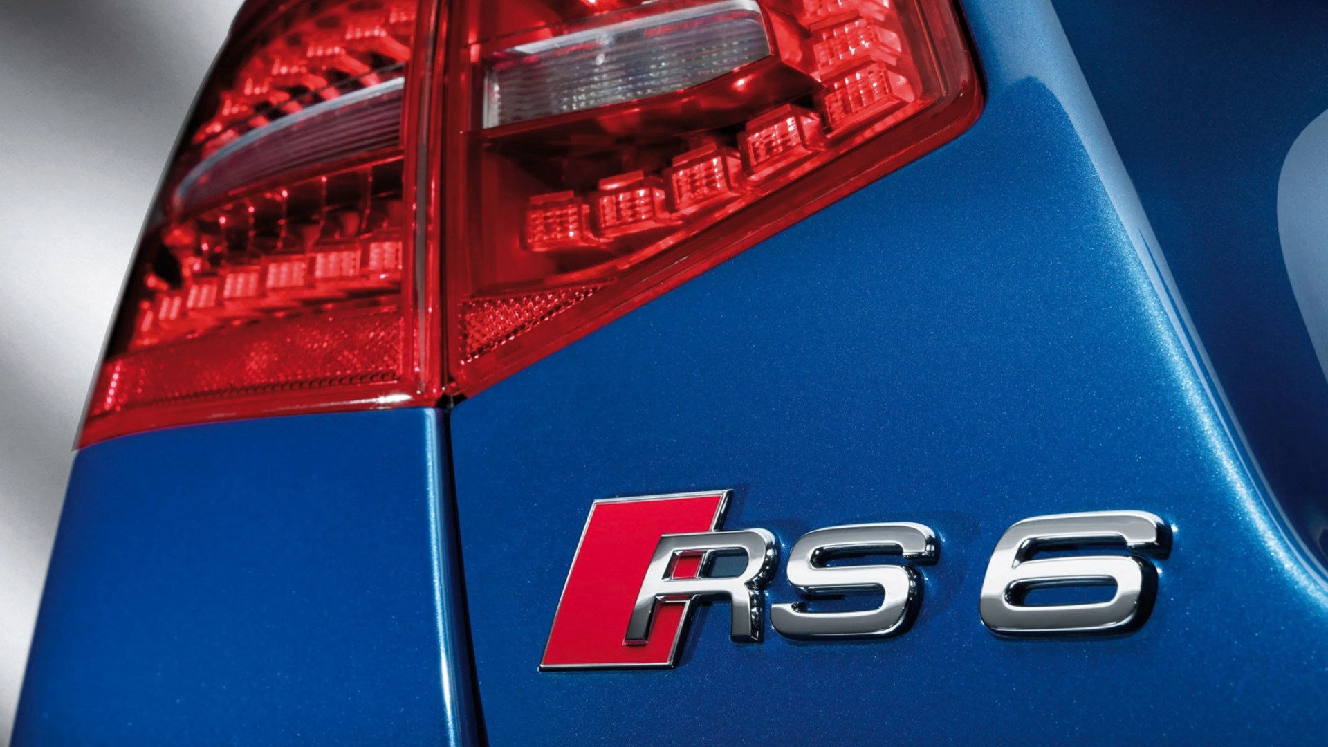 Close-up of a blue car's rear with red taillight and chrome RS 6 badge.