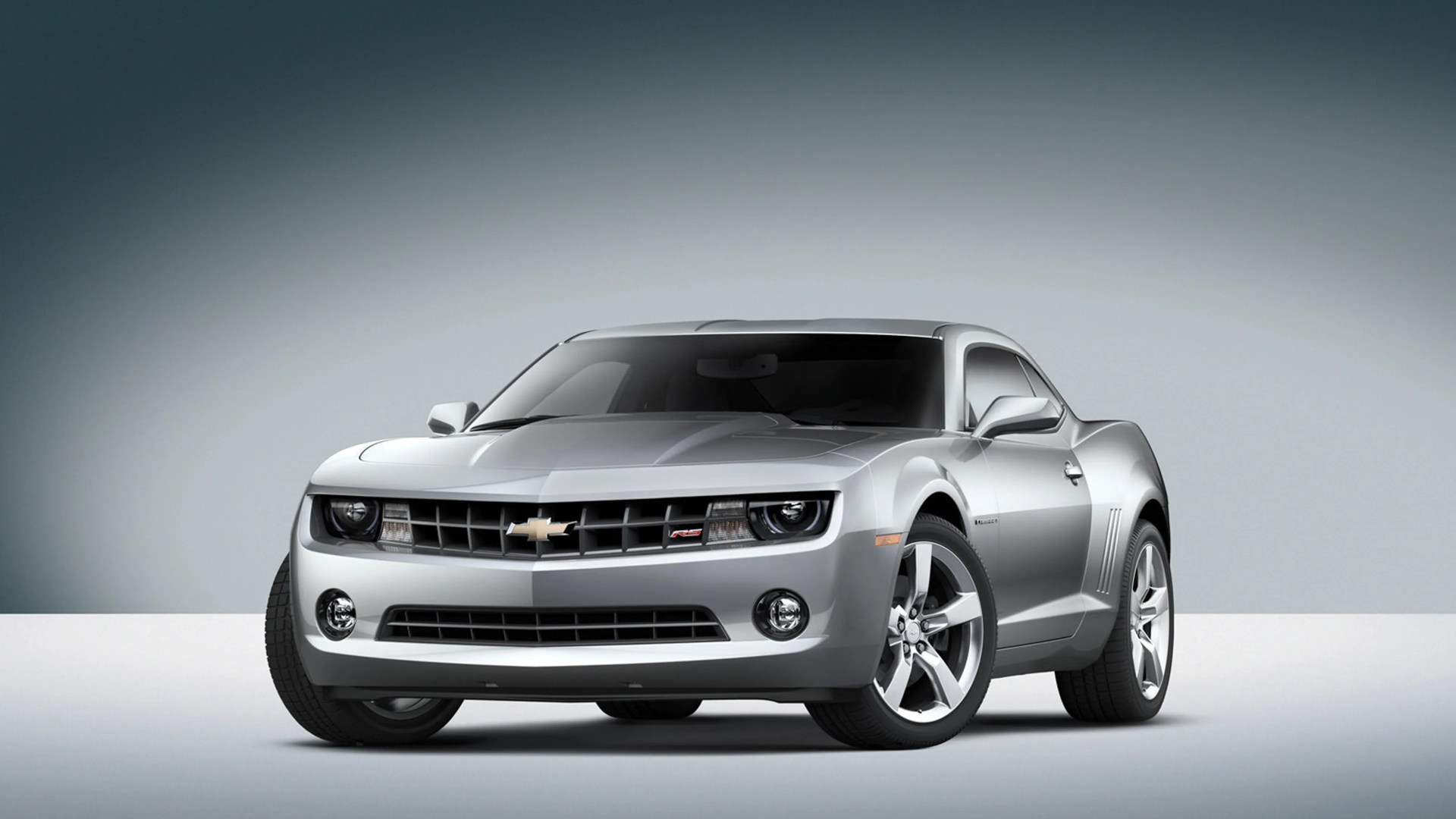 Silver Chevrolet Camaro RS coupe with tinted windows on a gray gradient background.
