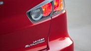 Close-up of red Mitsubishi Lancer Evolution rear with taillight and badge.