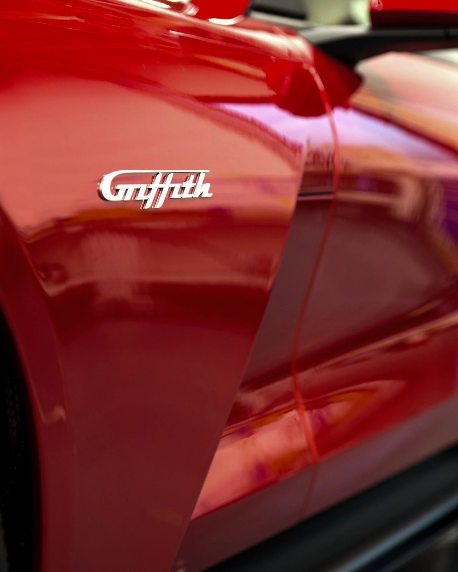 Close-up of a red car door with a silver "Griffith" emblem.