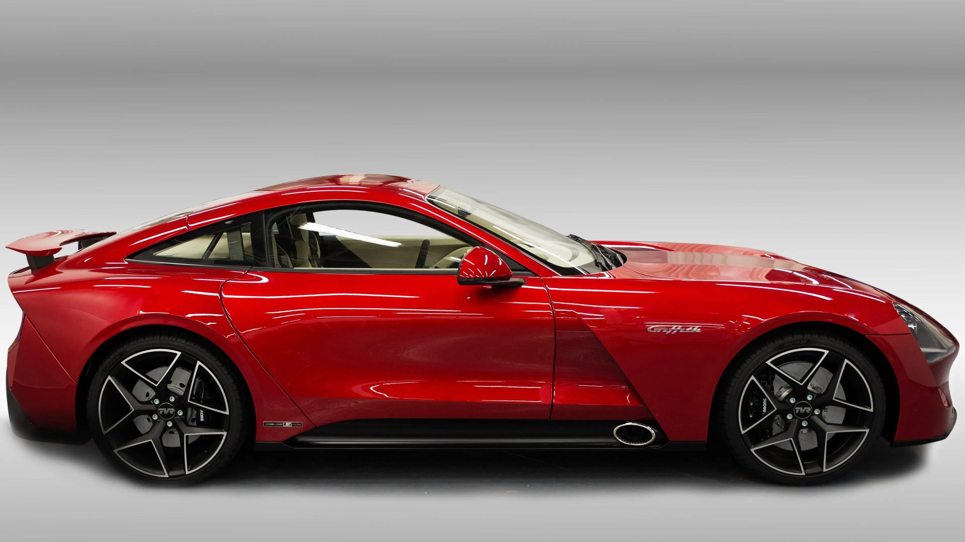 Red TVR Griffith sports car with black and silver five-spoke wheels and side exhaust pipe.