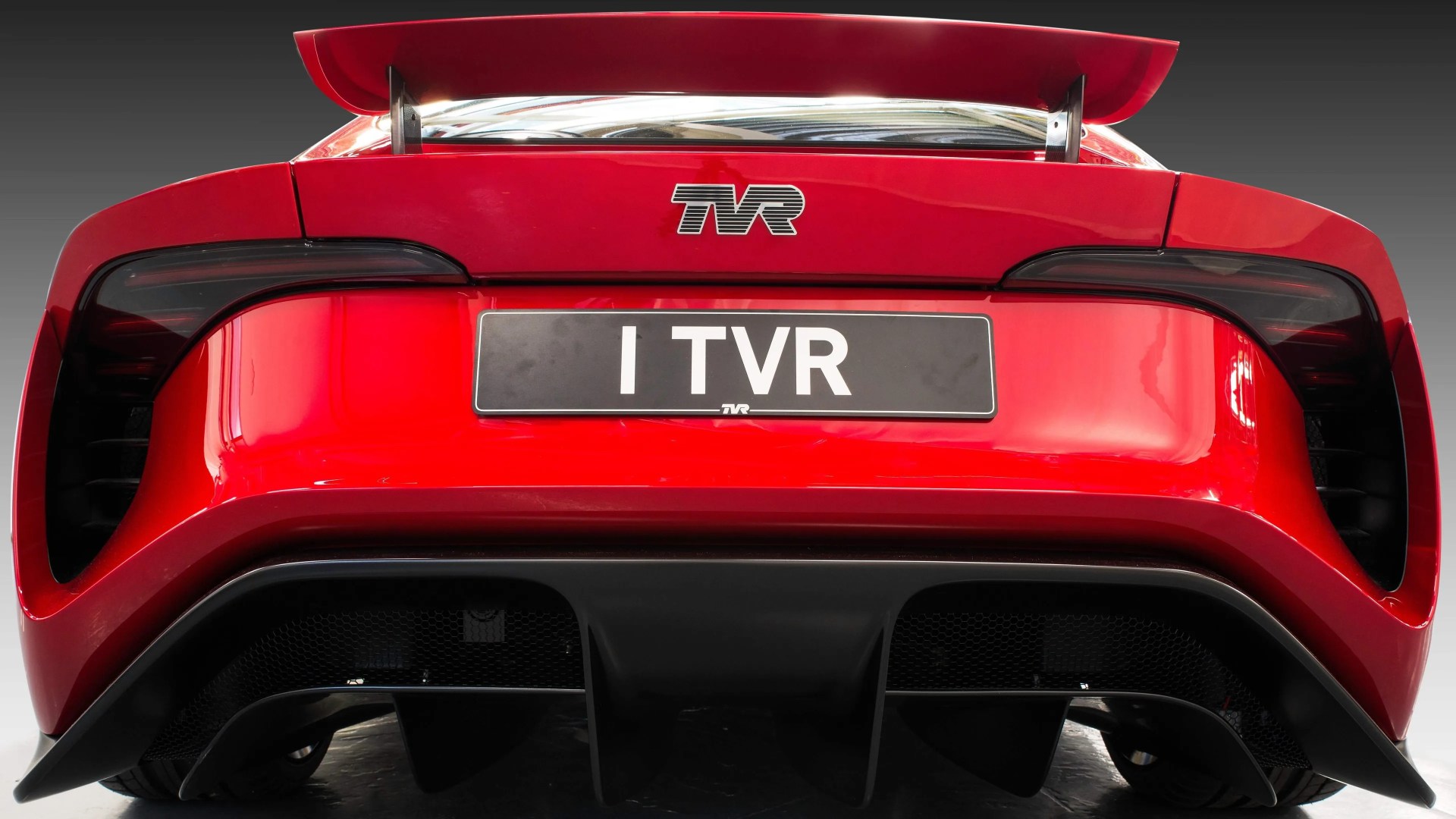 Rear view of a red TVR sports car with a black diffuser and a raised rear spoiler.