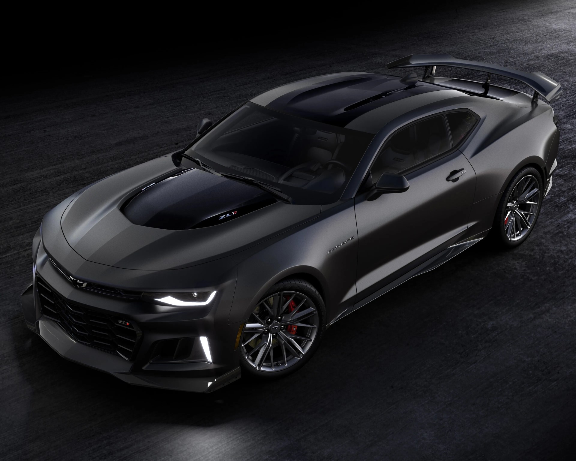 Matte black Chevrolet Camaro ZL1 with aggressive front splitter, hood scoop, and rear spoiler on dark asphalt.