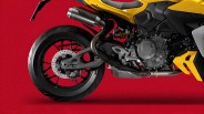 Close-up of the rear wheel, exhaust pipe, and engine area of a yellow motorcycle against a red background.