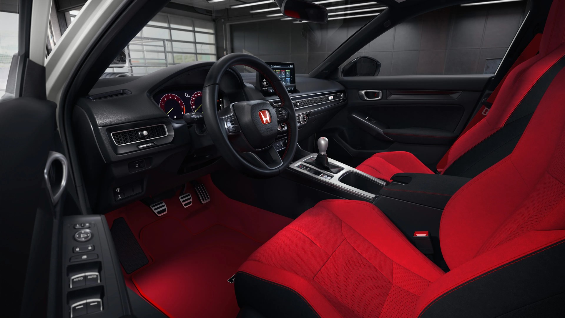 Car interior with red and black sport seats, black steering wheel with red Honda logo, manual gear shift, and red floor mats.
