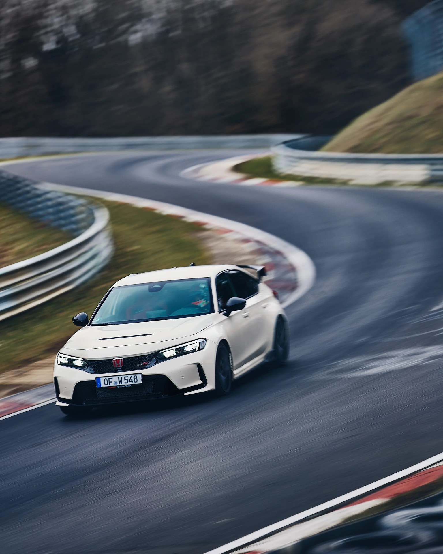White Honda Civic Type R with black accents drifting on a curved race track.