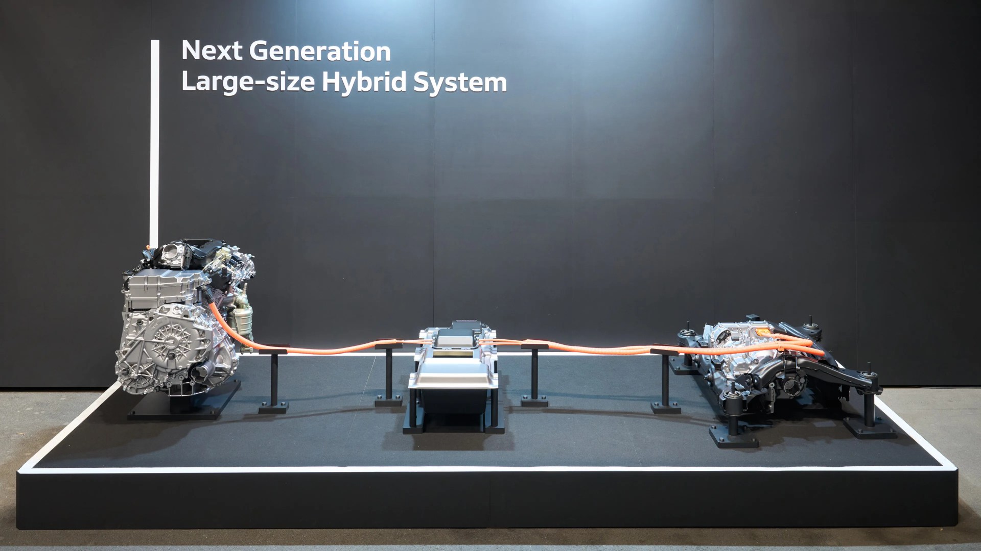 Next Generation Large-size Hybrid System components displayed on a platform with orange cables connecting them.