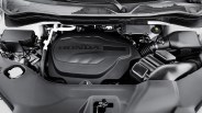 Black plastic engine cover with "HONDA" embossed, surrounded by various engine components in a car engine bay.