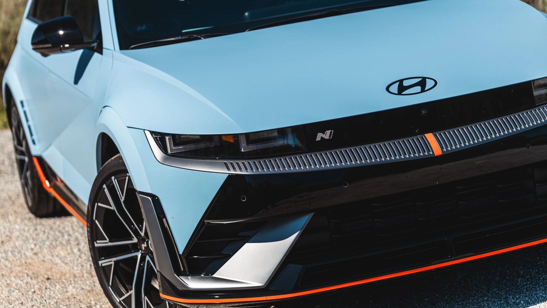 Light blue Hyundai car front with black grille, orange accents, and black alloy wheels.