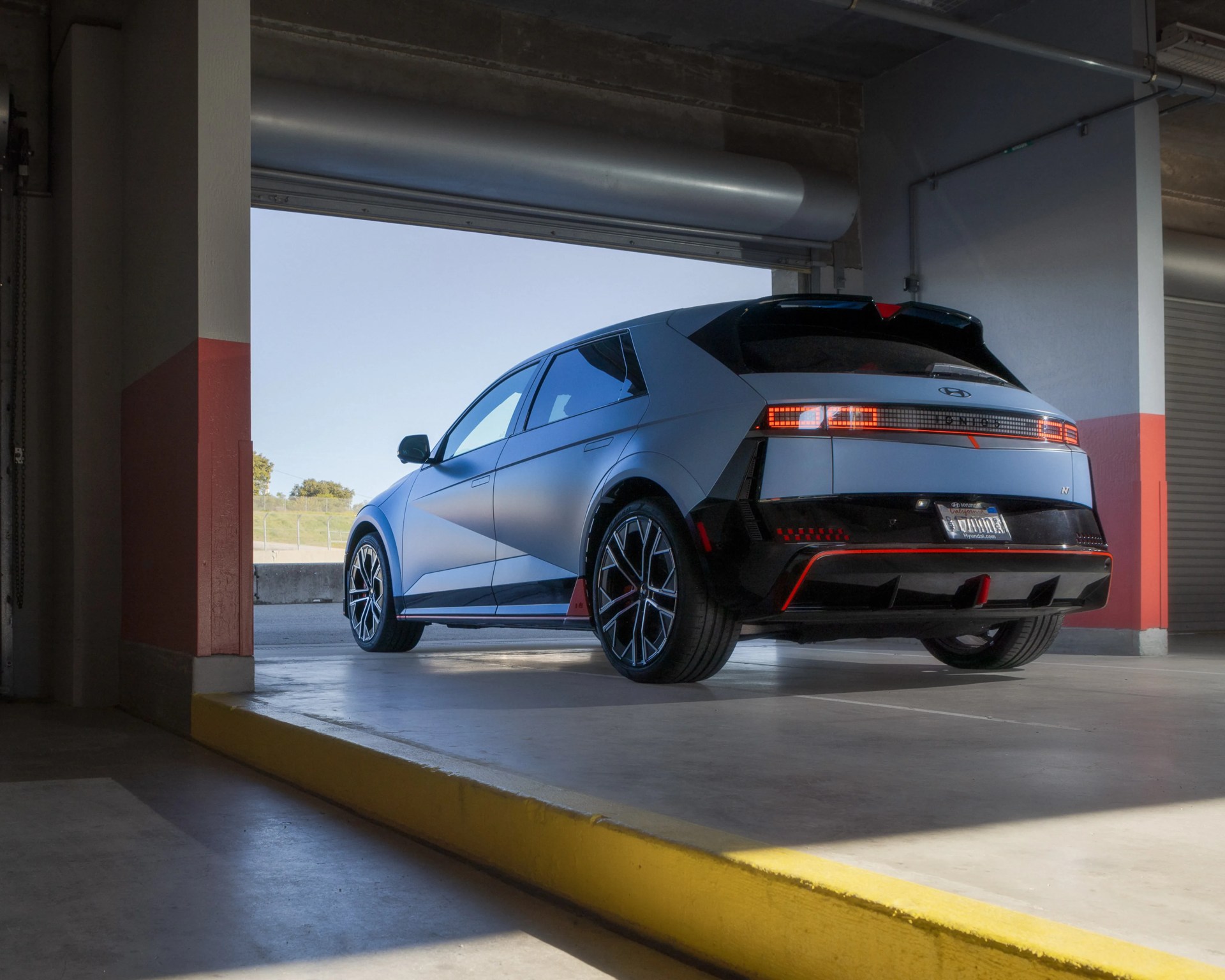 Matte gray Hyundai Ioniq 5 N electric SUV with black and red accents parked in a garage.