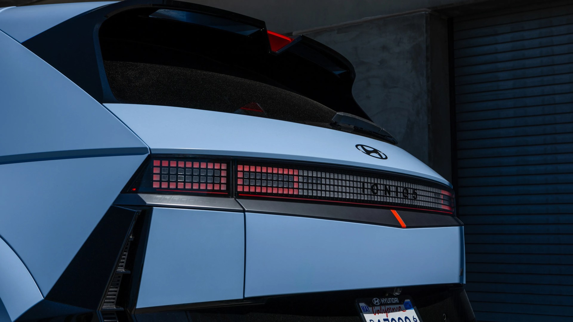 Rear view of a light blue Hyundai Ioniq 5 with pixelated red taillights and a California license plate.