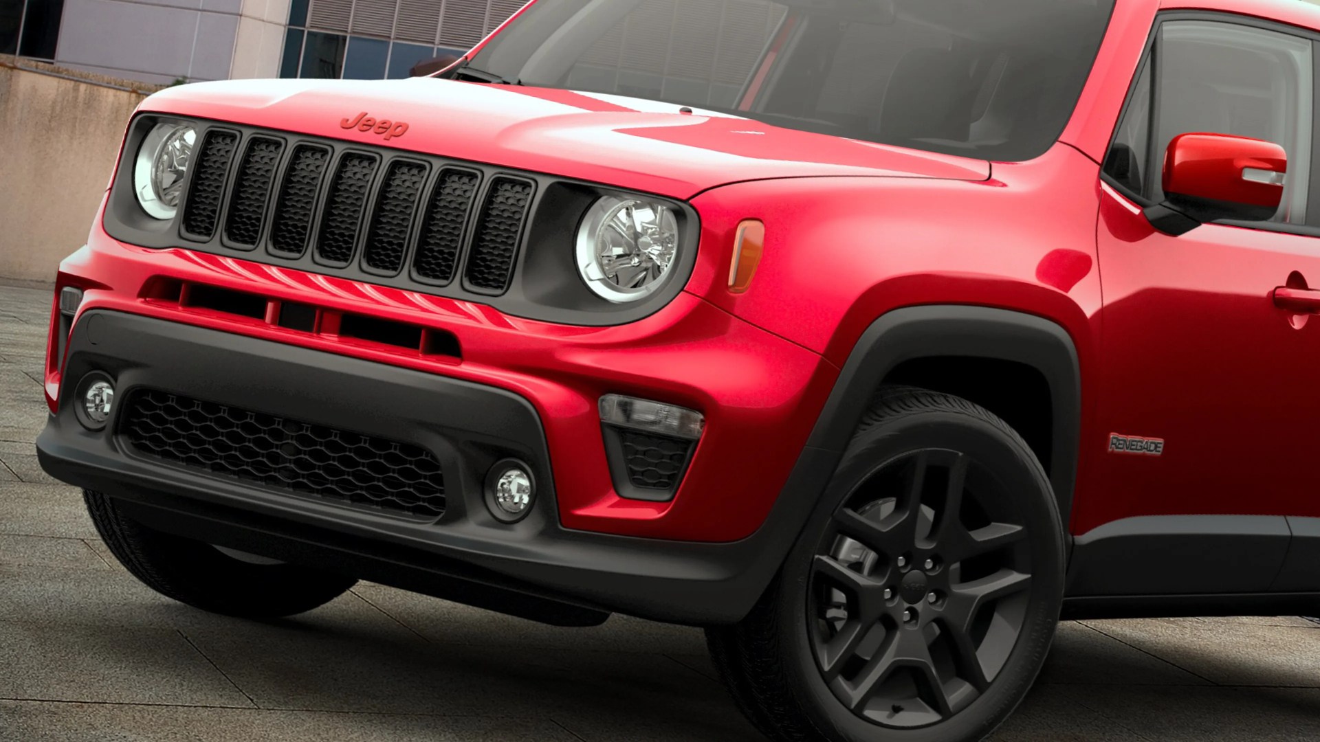 Front side view of a red Jeep Renegade with black grille and black alloy wheels.